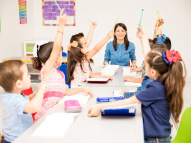 Kids raising their hands at school